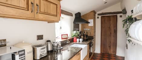 A kitchen with wooden cabinets, a granite countertop, a toaster, a kettle, and a sink.