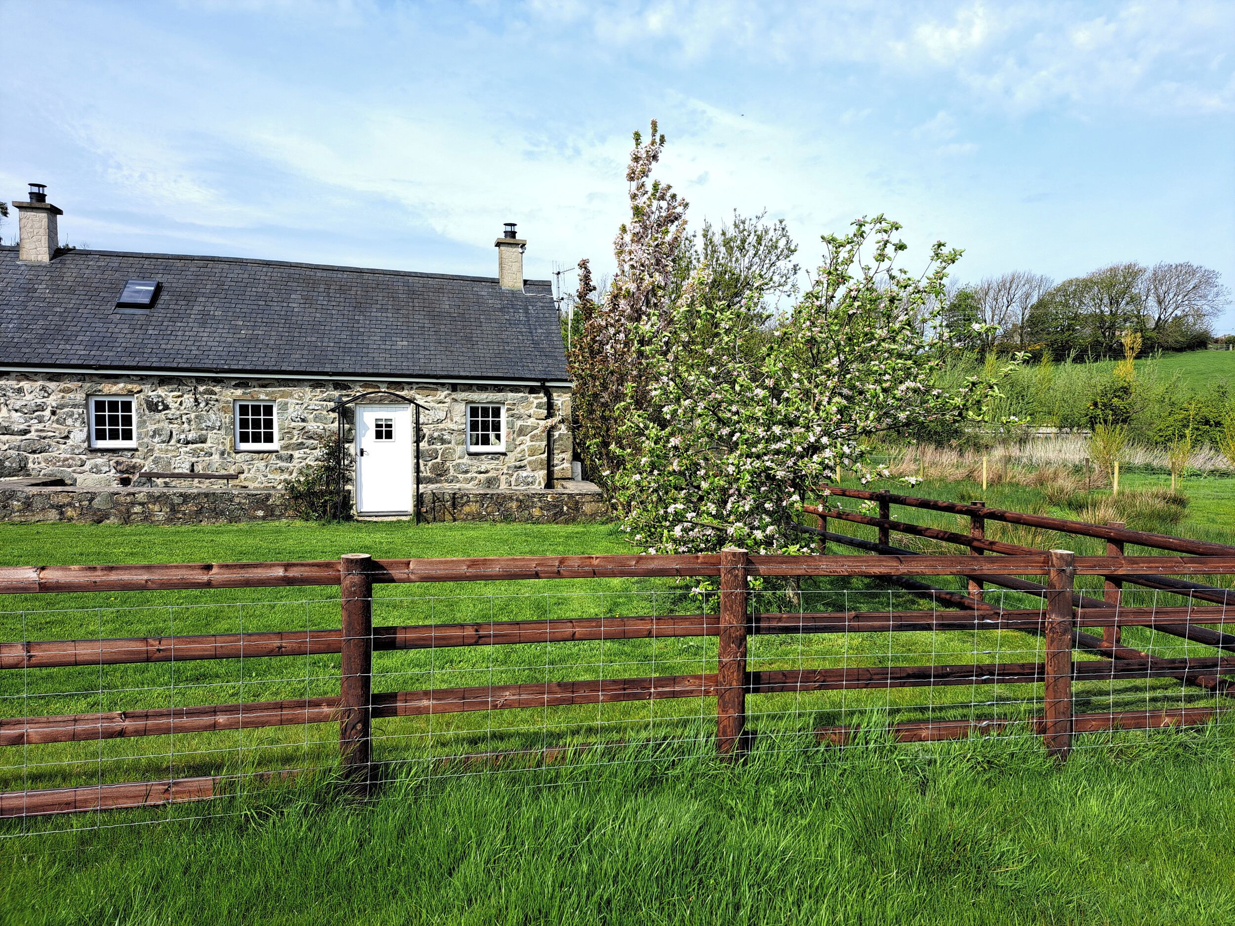 A stone house with a white door, a small window, and a chimney.