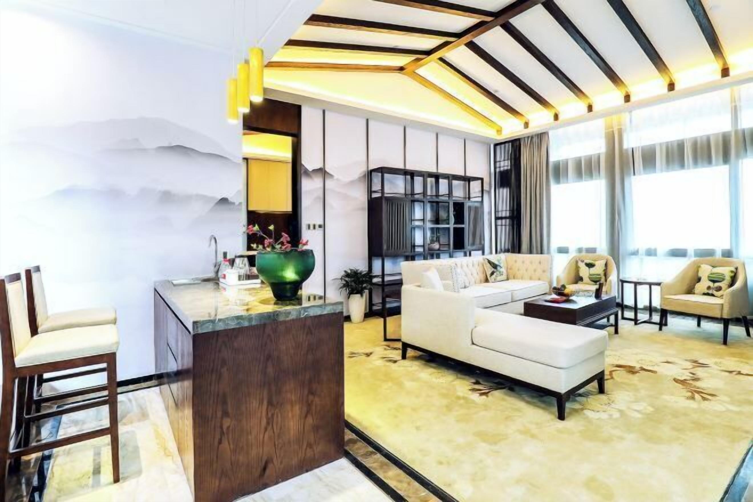 A modern living room with a sofa, armchairs, a coffee table, and a dining area.