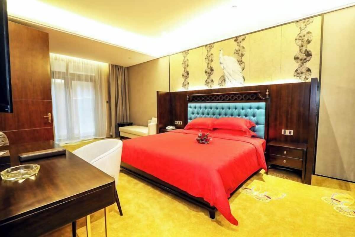 Een hotelkamer met een bed, nachtkastjes, een bureau en een stoel.