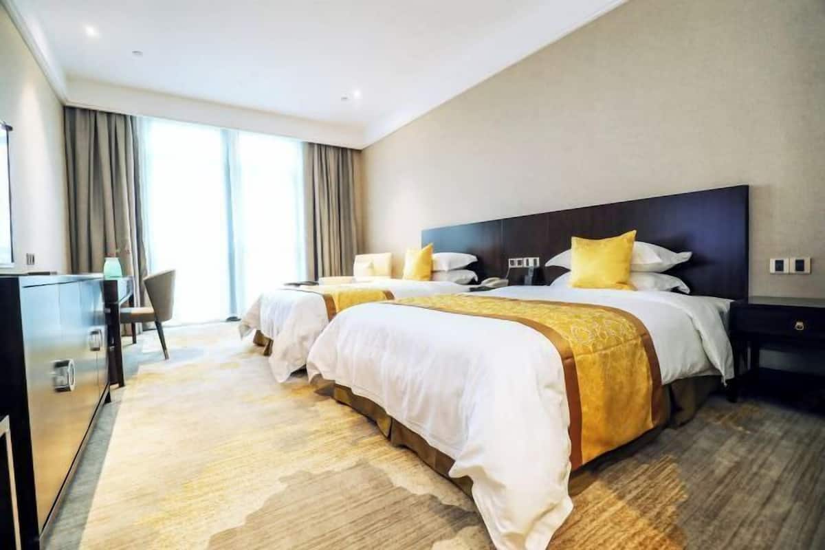 Een hotelkamer met twee bedden, een bureau en een groot raam.