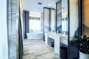 Une salle de bain moderne avec une baignoire aux lignes courbes, deux lavabos et un grand miroir.