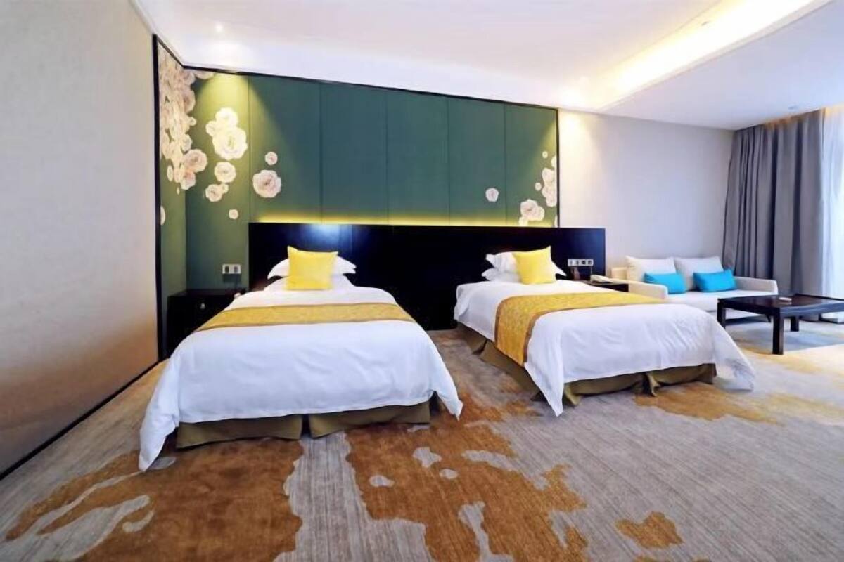 Een hotelkamer met twee bedden, een grote wandtelevisie en een modern design.