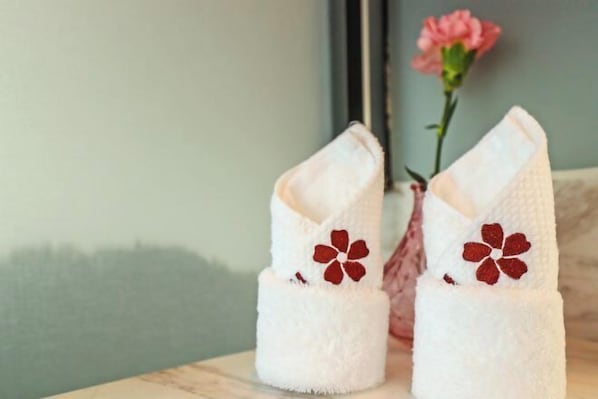 Two white towels with red floral designs placed on a surface.
