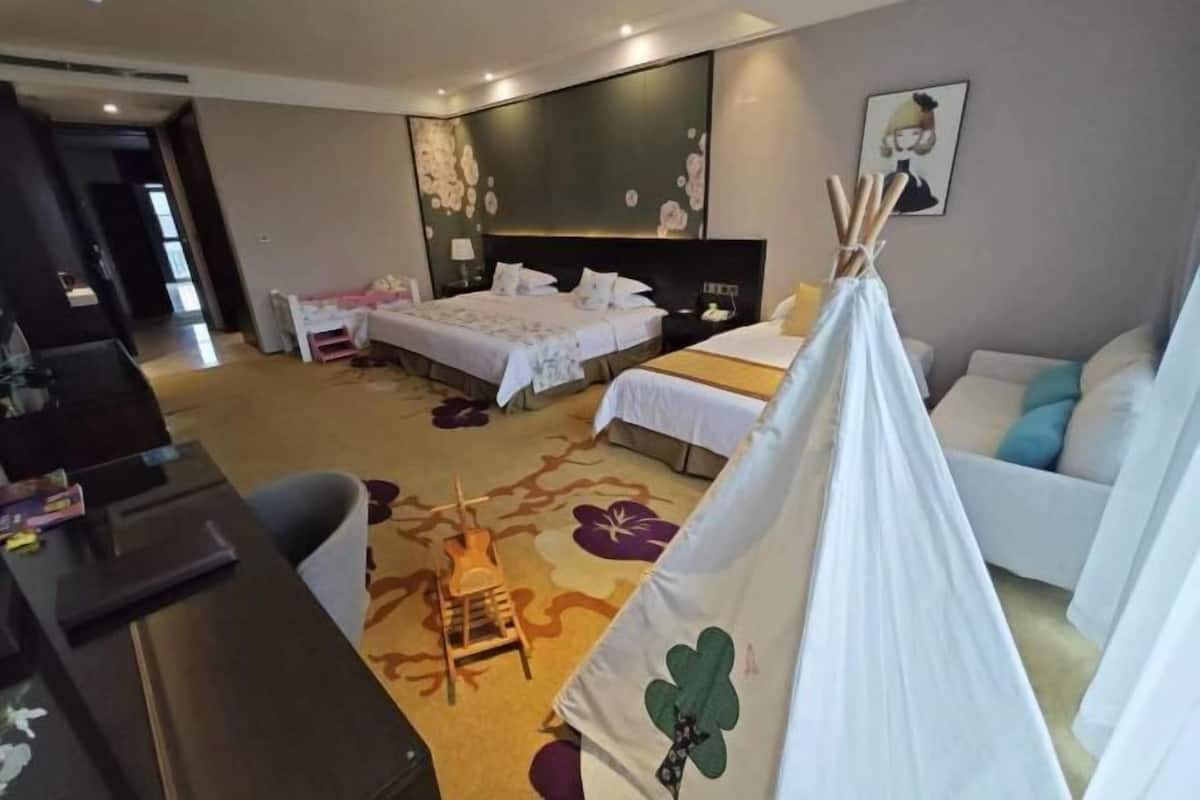 Hotelkamer met een bed, bureau, stoel, bank, een tentachtige constructie en een wand met bloemenprint.
