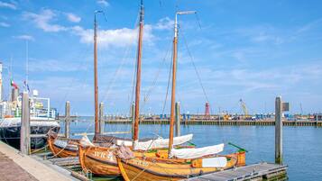 Un quai où sont amarrés plusieurs bateaux en bois, une jetée et un ciel d’un bleu limpide.