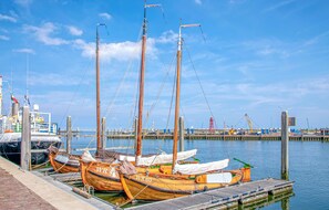 A dock with several wooden boats, a pier, and a clear blue sky. - Wieringen Waddenlodge (Den Oever)