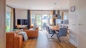 A modern living room with a sofa and a dining area with chairs and a table. - Wieringen Waddenlodge (Den Oever)