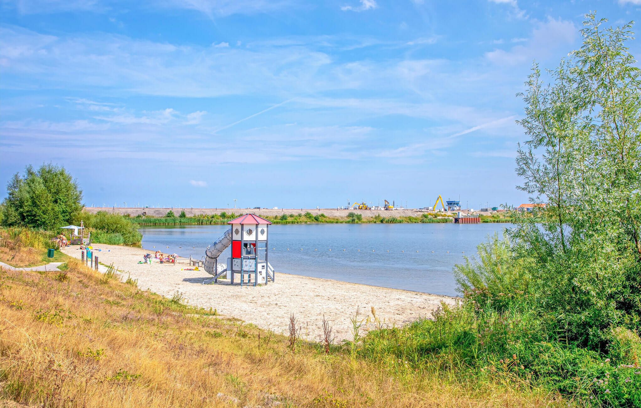 Une plage avec une tour de surveillance, un rivage sablonneux et une étendue d’eau calme.
