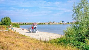 A beach with a lifeguard tower, sandy shore, and a calm body of water. - Wieringen Waddenlodge (Den Oever)