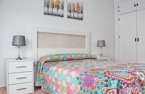 Une chambre à coucher comprenant un lit, deux tables de chevet, une armoire et deux tableaux accrochés au mur.