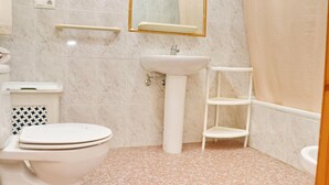 A bathroom with a toilet, sink, and a mirror.