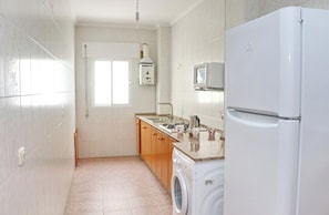 Eine kompakte Küche mit Waschmaschine, Mikrowelle und Kühlschrank.