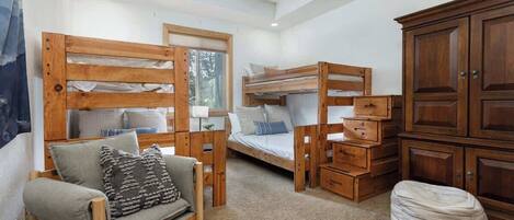 A cozy room with a bunk bed, a sofa, a cabinet, and a ceiling fan.