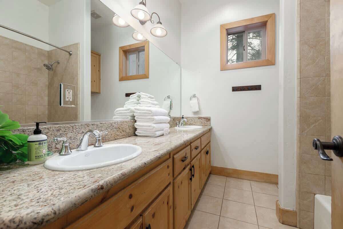 A bathroom with two sinks, a large mirror, and a shower.