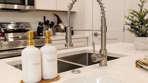 Une cuisine moderne avec des meubles blancs, des appareils en acier inoxydable et un robinet au design incurvé original.