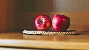 Two apples on a woven coaster on a wooden surface. - Studio Apartment 'Ferienwohnung Lanz 3' with Mountain View, Private Garden and Wi-Fi (Lana)