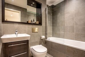A modern bathroom with a sink, toilet, and bathtub.