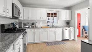 Una cocina moderna con armarios blancos, horno empotrado, microondas y lavavajillas.