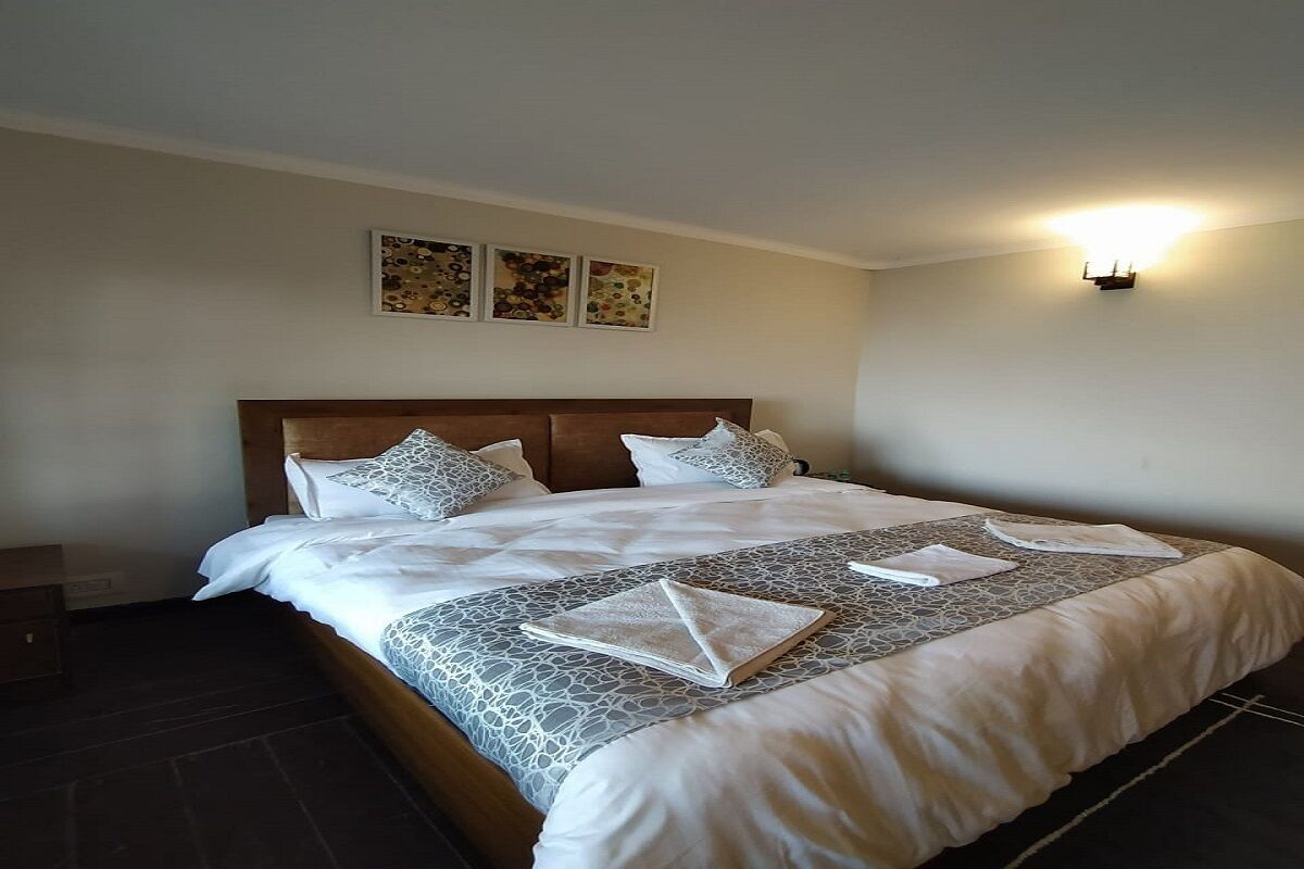Una cama bien hecha con una colcha estampada, dos almohadas y un cabecero.