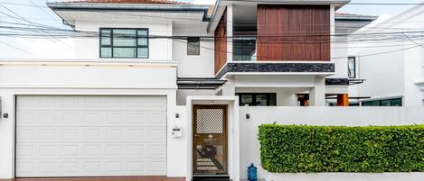 A modern two-story house with a white exterior, a garage, and a well-maintained garden.