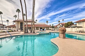 Relax by the serene pool surrounded by lush palm trees and a unique stone sculpture.