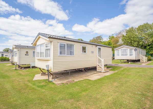 A mobile home with a porch, a small set of stairs, and a grassy yard.