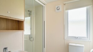 Une salle de bain avec une douche à parois de verre, des toilettes, un lavabo et une fenêtre.