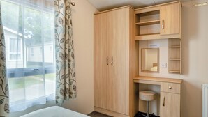 Une chambre à coucher comprenant un lit, une armoire, un bureau avec une chaise et une fenêtre avec des rideaux.