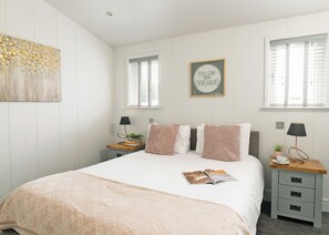 A neatly arranged bedroom with a bed, bedside tables, a wall art piece, and a motivational quote.