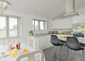 Une cuisine moderne avec des meubles blancs, une table à manger avec des chaises et un coin repas pour le petit-déjeuner.
