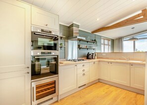 Una cocina moderna con electrodomésticos integrados, suelo de madera y un ventanal que proporciona luz natural.