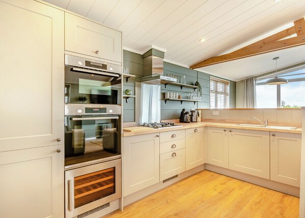 Una cocina moderna con electrodomésticos integrados, suelo de madera y un ventanal que proporciona luz natural.