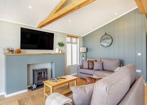 Una sala de estar con chimenea, un sofá, una mesa de centro, un televisor y un reloj en la pared.