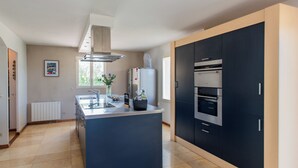 A modern kitchen with a central island, built-in oven, and a large window providing natural light. - Villa within walking distance of Flayosc (Flayosc)