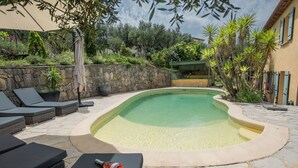 A swimming pool with a stone deck, surrounded by lounge chairs and potted plants. - Villa within walking distance of Flayosc (Flayosc)