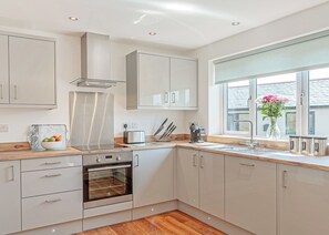 A modern kitchen with a built-in oven, stainless steel appliances, and a window with a view.