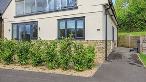 Une maison à deux étages avec un balcon, des fondations en pierre et un jardin de gravier.
