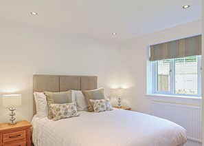 A bedroom with a bed, two bedside tables, a window with curtains, and recessed ceiling lights. - 2 bedroom accommodation in Glastonbury (Glastonbury)