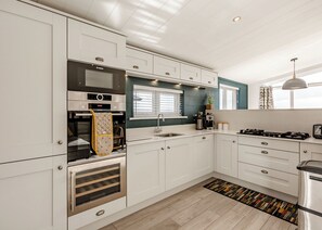Una cocina moderna con armarios blancos, un horno Bosch, una cafetera y una estufa a gas.