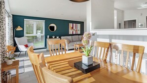 A dining area with a wooden table, chairs, and a central vase with flowers. - Luxurious lodge with vaulted ceilings and a welcoming feature fireplace. (Glastonbury)