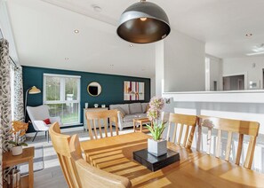Un comedor con una mesa de madera, sillas y un jarrón central con flores.