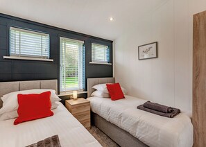 Un dormitorio con dos camas, una mesita de noche y una ventana con persianas.
