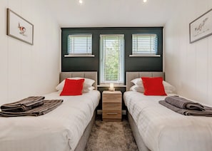 Une chambre avec deux lits, une table de chevet et une fenêtre avec des stores.