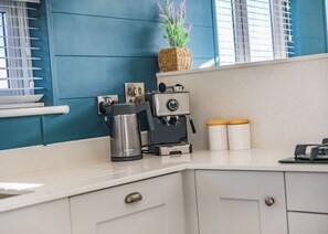 A kitchen with a coffee machine, a toaster, and two white containers on the counter.