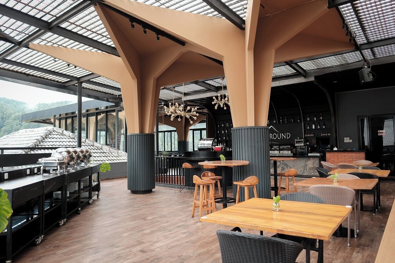 A restaurant with a modern interior, featuring high ceilings, a bar area, and a view of the mountains.