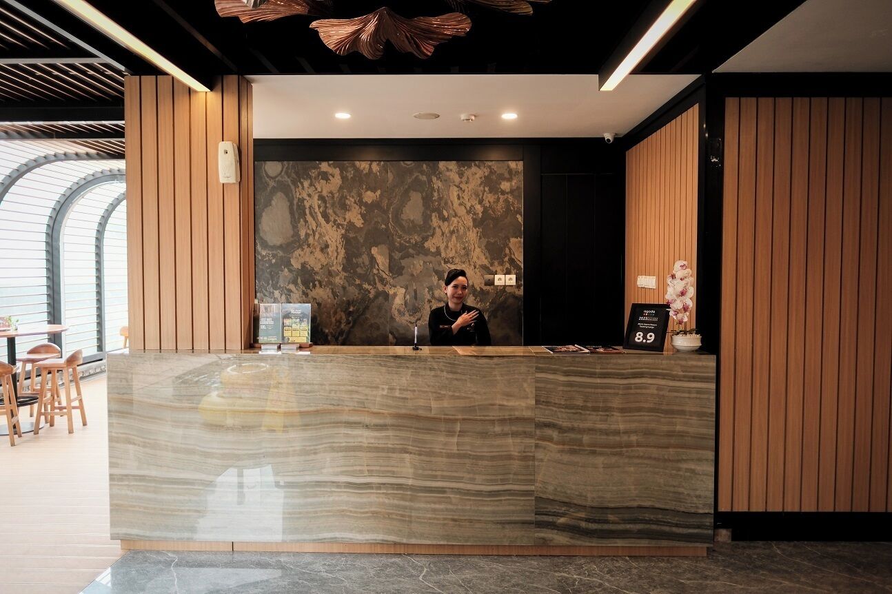 A reception desk with a marble top, a receptionist, and a wall with a textured pattern.