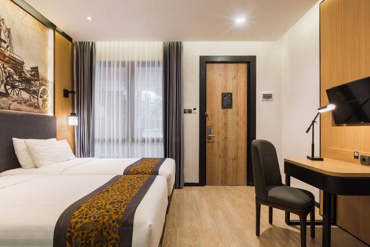 A hotel room with a large bed, a desk, a chair, and a television.