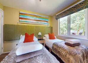 Hotelkamer met twee bedden, een raam met uitzicht, een schilderij aan de muur en een kamerbreed gordijn.