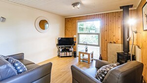 A living room with a television, books, and a fireplace. - Stylish open plan lodge with king-size four poster bed. (Harrogate)
